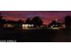 Street view of community at night with dark red sky and homes adorned with holiday lights at 10816 W Venturi Dr, Sun City, AZ 85351