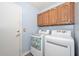 Laundry room showcasing a door and white washer and dryer with oak cabinets above at 12425 N 127Th Dr, El Mirage, AZ 85335