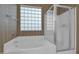 Bright bathroom features a soaking tub, glass block window, and separate glass-enclosed shower at 12607 W Highland Ave, Litchfield Park, AZ 85340