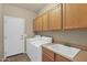 Laundry room includes a washer, dryer, sink, and overhead cabinets at 12607 W Highland Ave, Litchfield Park, AZ 85340