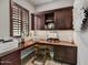 This office space has built-in cabinets, a workstation, a window with shutter, and wood-style floors at 12970 W Kokopelli Dr, Peoria, AZ 85383