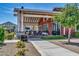 Exterior view of the clubhouse featuring a covered seating area, manicured landscaping, and signage at 17165 W Piperton St # 181, Surprise, AZ 85388