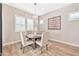 Cozy dining room featuring a round wooden table, four chairs, plantation shutters, and modern decor at 17165 W Piperton St # 181, Surprise, AZ 85388