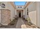 Inviting front entrance with a stone column, tiled walkway, mature plants, and a stylish security door at 17165 W Piperton St # 181, Surprise, AZ 85388