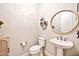 Stylish powder room featuring a round mirror, pedestal sink, and decorative wall shelves at 17165 W Piperton St # 181, Surprise, AZ 85388
