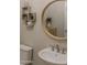 Trendy powder room featuring a round mirror, pedestal sink, and decorative wall shelves at 17165 W Piperton St # 181, Surprise, AZ 85388