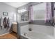 This bathroom showcases a soaking tub, neutral color palette and a large window at 17286 W Morning Glory St, Goodyear, AZ 85338