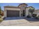 A tan single-story home showcasing a two-car garage and an arched gate entrance at 1775 E Tangelo Pl, Queen Creek, AZ 85140