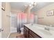 Well-lit bathroom with double sink vanity and shower with pink and white curtain at 20728 W Legend Trl, Buckeye, AZ 85396