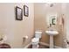 Powder room with a pedestal sink, toilet, and decorative hanging art at 20728 W Legend Trl, Buckeye, AZ 85396