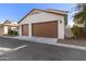 A well-maintained three-car garage with brown doors and a clean driveway, perfect for ample parking and storage at 20728 W Legend Trl, Buckeye, AZ 85396