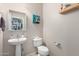 Well-lit half bathroom featuring a modern sink and toilet at 26111 W Yukon Dr, Buckeye, AZ 85396
