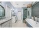 A blue-themed bathroom with dual sinks, stone countertops, a glass shower, and a classic freestanding tub at 2733 E Virginia St, Gilbert, AZ 85296