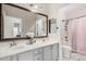 Bathroom with a double sink vanity, decorative mirror, and a shower with a pink curtain at 30427 W Vale Dr, Buckeye, AZ 85396