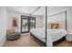 Bright bedroom with a four-poster bed, a view of the outdoor landscape, and a patterned ottoman at 4434 E Camelback Rd # 128, Phoenix, AZ 85018