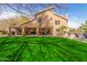 Well-maintained backyard with lush green lawn, covered patio, and view of the home's exterior at 4937 W Desert Hollow Dr, Phoenix, AZ 85083