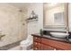 Well-lit bathroom featuring a tiled shower, dark granite countertop, vessel sink, and elegant fixtures at 4937 W Desert Hollow Dr, Phoenix, AZ 85083