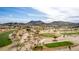 Scenic aerial view of a golf course featuring lush greens, sandy areas, and distant mountains at 4937 W Desert Hollow Dr, Phoenix, AZ 85083