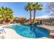 Sparkling blue swimming pool with mature palm trees and rock waterfall feature in the backyard at 4937 W Desert Hollow Dr, Phoenix, AZ 85083