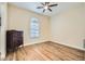 Clean bedroom features a ceiling fan, arched window and wood floors with a classic dresser for storage at 5225 S Opal Pl, Chandler, AZ 85249