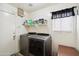 Bright laundry room with modern washer and dryer units, and a storage shelf at 62 N 221St Ave, Buckeye, AZ 85326