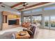 Bright living room with beamed ceiling, fireplace, and scenic views from the large glass doors at 669 W Chaparral Rd, Wickenburg, AZ 85390