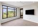 Sunlit bedroom with balcony access and a mounted flatscreen television at 7175 E Camelback Rd # 307, Scottsdale, AZ 85251