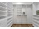 Spacious walk-in closet features wood floor and extensive white shelving and hanging areas for storage at 8713 N 80Th Pl, Scottsdale, AZ 85258