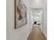 Hallway features wood floors and white walls with an art piece leading to bedroom with an open door at 8713 N 80Th Pl, Scottsdale, AZ 85258