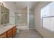 Bright bathroom featuring a shower-tub combination with glass doors and a separate glass enclosed shower at 9325 W Hazelwood St, Phoenix, AZ 85037