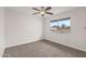 Bright bedroom featuring neutral carpet, a ceiling fan, and a window looking to the backyard at 10956 W Meade Dr, Sun City, AZ 85351