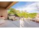 This backyard patio features wicker furniture and a large tree for shade, perfect for entertaining at 15237 S 47Th Way, Phoenix, AZ 85044