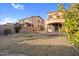 View of backyard and stucco home with covered patio, manicured lawn and fruit tree at 15635 W Montecito Ave, Goodyear, AZ 85395