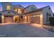 Elegant two-story home featuring a three-car garage, arched entryway, gated courtyard, and tile roof in a warm neutral palette at 15635 W Montecito Ave, Goodyear, AZ 85395