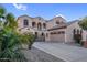 Elegant two-story home featuring a three-car garage, arched entryway, gated courtyard, desert landscaping and a tile roof at 15635 W Montecito Ave, Goodyear, AZ 85395