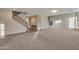 Spacious carpeted living room with staircase, large windows, a console table, and seamless transition to the tiled entryway at 15635 W Montecito Ave, Goodyear, AZ 85395