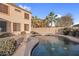 A tranquil private backyard pool with a two-story home in the background and bordered by lush palm trees at 15635 W Montecito Ave, Goodyear, AZ 85395