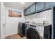 Laundry room with front-load washer and dryer, subway tile backsplash, and upper cabinets at 19333 N 68Th Ave, Glendale, AZ 85308