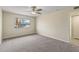 This bedroom features a ceiling fan, a large window, neutral carpet, and access to the ensuite at 20210 N 124Th Dr, Sun City West, AZ 85375