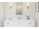 Close up on a white vanity with a mirror reflecting a shower, lit by sconces, and adorned with decor at 2024 N Woodburne Pl, Chandler, AZ 85224