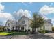 Charming two-story white brick home showcasing lush green lawns and mature trees under a bright, cloudy sky at 20406 E Sunset Ct, Queen Creek, AZ 85142