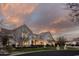 Elegant light-colored brick home with manicured landscaping, set against a striking sunset sky at 20406 E Sunset Ct, Queen Creek, AZ 85142