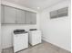 Neat laundry room with gray cabinets, window, and modern appliances at 20660 N Confetti Ct, Maricopa, AZ 85138