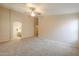 Spacious main bedroom featuring a ceiling fan, neutral carpet, and an ensuite bathroom entrance at 22139 N Van Loo Dr, Maricopa, AZ 85138