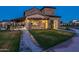 Striking nighttime exterior view of the clubhouse featuring a stone facade, covered patio, and lush green lawn at 2779 E Derringer Way, Gilbert, AZ 85295