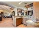 A kitchen and hallway featuring stone floors, arched doorways, custom cabinets, and granite countertops at 3756 N Rock Wren Ct, Buckeye, AZ 85396