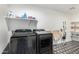 Well-organized laundry room with side-by-side black washing machines and ample shelving for storage at 3760 E Cotton Ct, Gilbert, AZ 85234