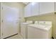 Bright laundry room featuring a white washer and dryer, white cabinets, a door, and tiled flooring at 41225 N River Bend Rd, Phoenix, AZ 85086