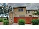 Tan townhouse with a red brick gate, trimmed shrubbery, and a healthy shade tree on a cloudy day at 625 S Westwood St # 108, Mesa, AZ 85210