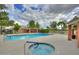 Community pool and hot tub surrounded by lounge chairs, greenery, and palm trees on a partly cloudy day at 625 S Westwood St # 108, Mesa, AZ 85210